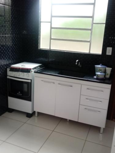 a kitchen with a stove and a sink and a window at Pousada Recanto Rocha in Arambaré