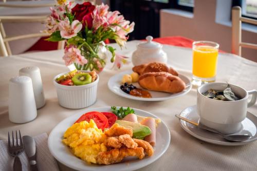 een tafel met borden ontbijtproducten en een kopje jus d'orange bij La Casa de Fray Bartolome in Cuzco