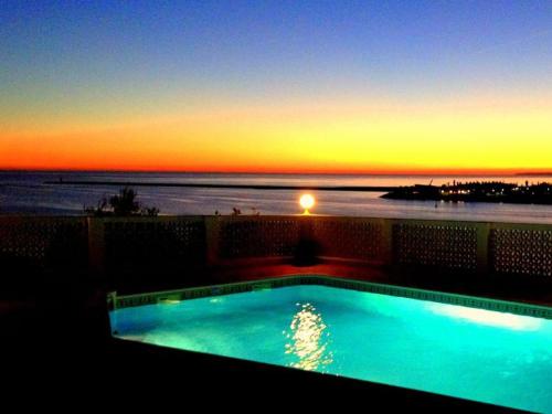 a swimming pool with the sunset in the background at Vila Monte Luz in Ferragudo