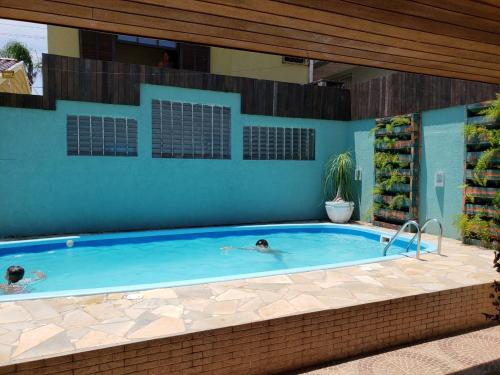 two people are swimming in a swimming pool at Casa em Guaratuba com piscina in Guaratuba