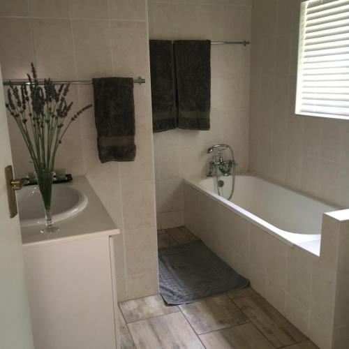 a bathroom with a tub and a vase of flowers at Idavold Cottages in Howick