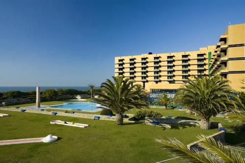 un complexe avec une piscine, des palmiers et un bâtiment dans l'établissement Hotel Solverde Spa and Wellness Center, à Vila Nova de Gaia