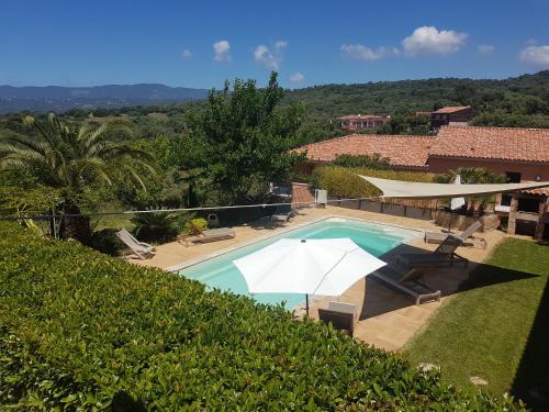 une piscine avec des parasols et une maison dans l'établissement sci marie dominique, à Olmeto