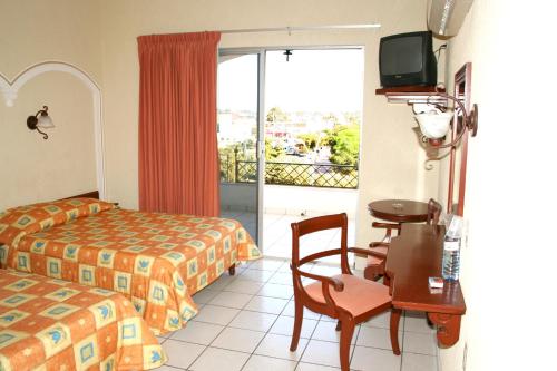 a hotel room with a bed and a desk with a table at Hotel Davimar in Guamúchil