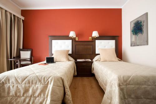 two beds in a hotel room with red walls at Achillion Palace in Rethymno