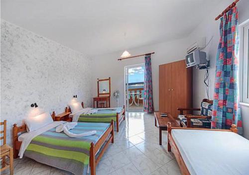 a hotel room with three beds and a television at Kastro Kera in Almyrida