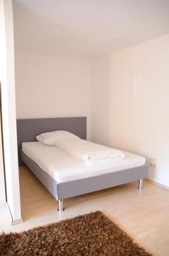 a white bed in a room with a white wall at LMS Apartments in Weiterstadt