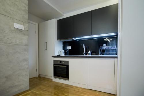 a kitchen with white cabinets and black appliances at Apartment Exclusive and Studio in Subotica