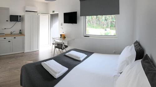 a bedroom with a large bed with white sheets and a window at Quinta do Meco - Beach & Nature in Aldeia do Meco
