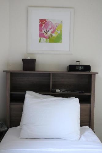 a bed with a wooden headboard and a picture on the wall at Midtown West Hotel in New York