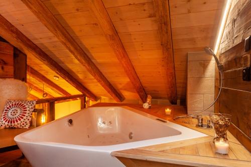 ツェルマットにあるChalet Schulerの木製の天井の客室で、白い大型バスタブが備わります。