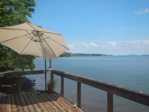 an umbrella sitting on a deck next to the water at Beached Bungalow Overlooking the Pacific Ocean in Boca Chica