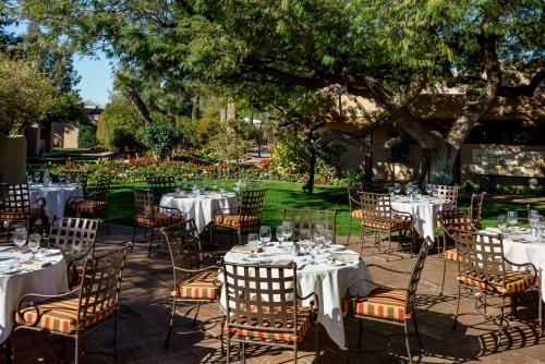 a group of tables and chairs in a garden at The Hermosa Inn in Phoenix