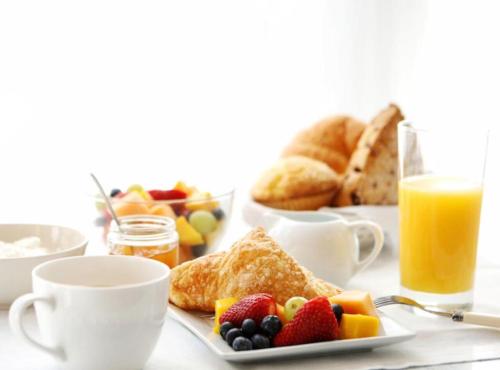 una mesa con un plato de desayuno y tazas de zumo de naranja en Hotel Royal Saranda, en Sarandë