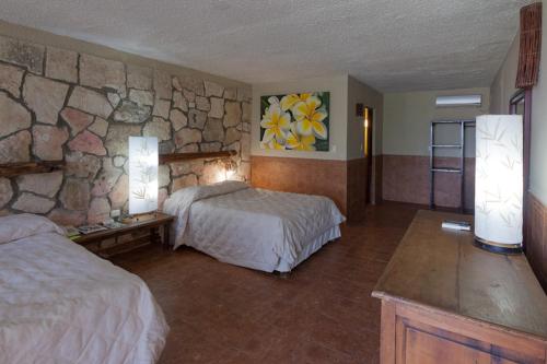 a hotel room with two beds and a stone wall at Blue Angel Resort in Cozumel
