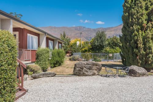 a garden with a table and chairs and trees at Manuka Crescent Motel in Wanaka