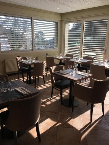 a dining room with tables and chairs and windows at Hotel Restaurant au Floridor in Thann
