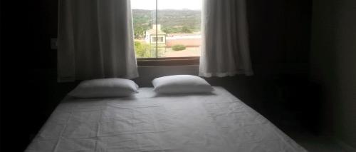 a bed with two pillows in a room with a window at Topázio Park Hotel in Afrânio
