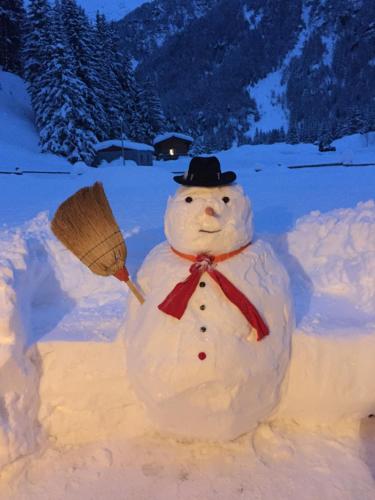 a snowman with a hat and a broom at Alpine Chalet in Santa Caterina Valfurva
