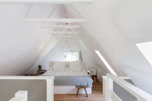 a white bedroom with a bed in a attic at De Rheezer Kamer in Hardenberg