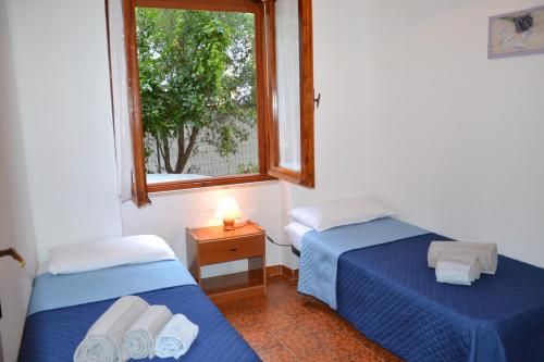 two beds in a room with a window at Confortevole appartamento a pochi passi dal mare in Cala Gonone