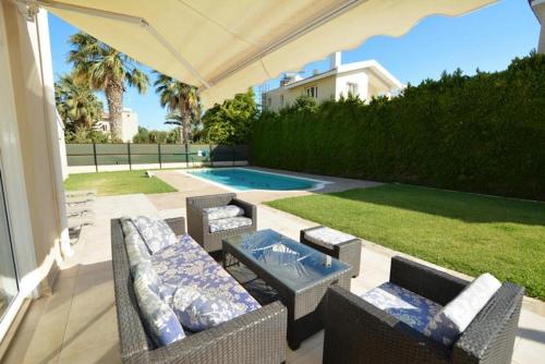 a patio with chairs and a table and a pool at Villa Daryah Sirina Bay in Protaras