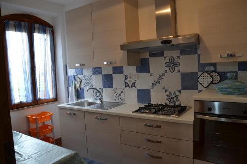 uma cozinha com um lavatório e um fogão forno superior em Confortevole appartamento a pochi passi dal mare em Cala Gonone