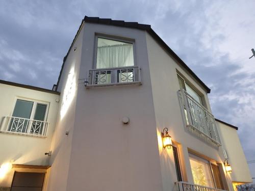 a white house with two windows and a sky at HANI Haus in Jeju