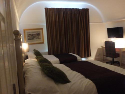 a bedroom with a bed and a desk and a window at Jessamine House Hotel in Gravesend