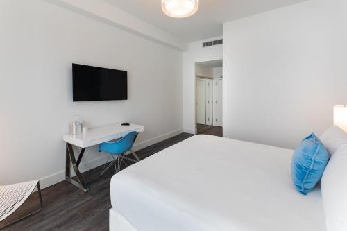 a bedroom with a bed and a desk and a tv at President Hotel in Miami Beach