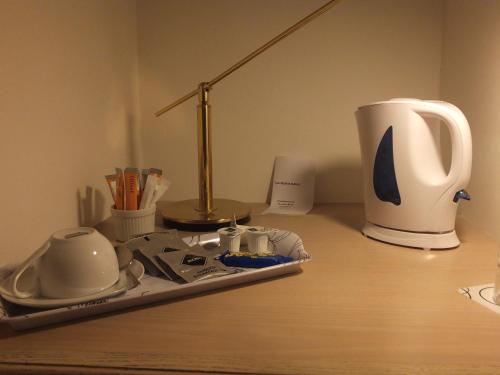 a desk with a lamp and a cup on it at Jessamine House Hotel in Gravesend