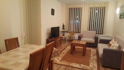ein Wohnzimmer mit einem Sofa, einem Tisch und einem TV in der Unterkunft Ski Apartment D50 Cedar Lodge 4 in Bansko