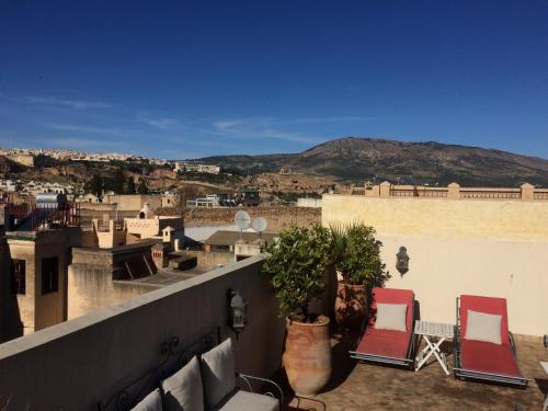 a balcony with two chairs and a view of a city at Dar Abdesalam in Fès