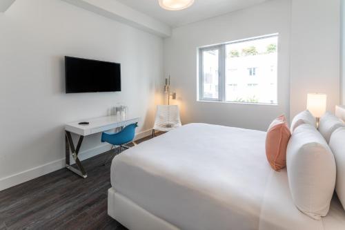 a white bedroom with a bed and a desk at President Hotel in Miami Beach