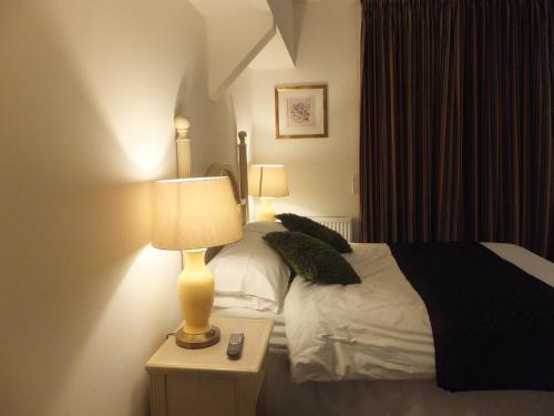 a hotel room with a bed and a lamp on a table at Jessamine House Hotel in Gravesend