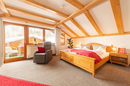 a bedroom with a large wooden bed and a chair at "Haus Alpenblick" - Annehmlichkeiten von 4-Sterne Familien-und Wellnesshotel Viktoria können mitbenutzt werden in Oberstdorf