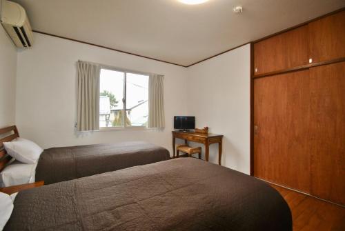 鎌倉市にある女性専用 Inn By The Sea Kamakura - Women's Guesthouseのベッド2台と窓が備わるホテルルームです。