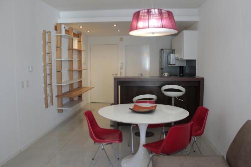 a kitchen and dining room with a white table and red chairs at Palermo nuevo - Embajada USA in Buenos Aires