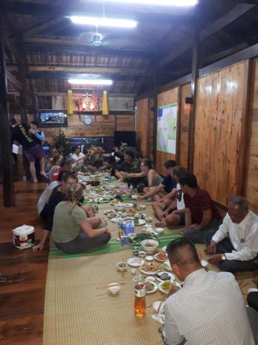 Linh Homestay and motorbikes rent في ها زانغ: مجموعة من الناس يجلسون حول طاولة طويلة مع الطعام
