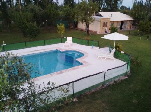 een zwembad met 2 stoelen en een parasol bij Cabañas Terra Olivo in Coquimbito