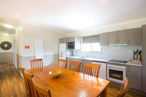a kitchen with a wooden dining table and chairs at Halifax Holiday Park in Nelson Bay