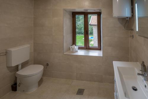 a bathroom with a toilet and a sink and a window at Stara kuća Estate in Ljubuški