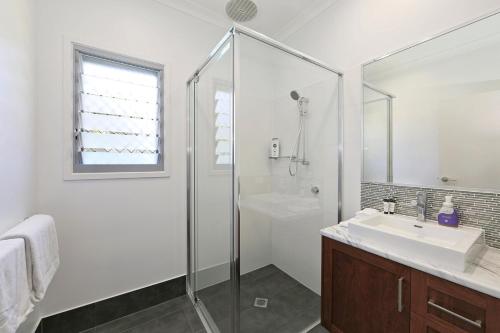 a white bathroom with a sink and a shower at 12th Tee BnB in Bargara
