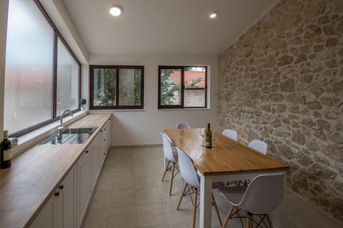 a kitchen with a wooden table and a stone wall at Stara kuća Estate in Ljubuški