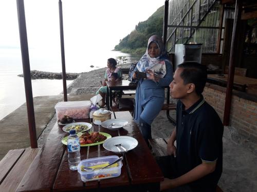 a man and a woman sitting at a table with food at Pondok Berata Dapdap in Balige