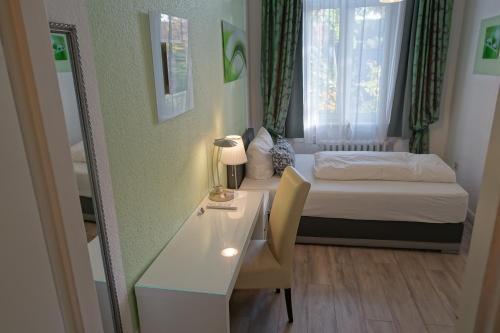 a small room with a bed and a desk with a desk at Hotel Villa Konstanz in Berlin
