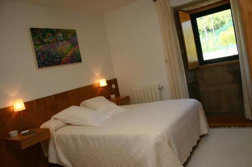 a bedroom with a white bed and a window at Casa rural A Mimoseira in A Estrada