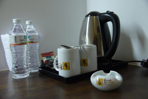 a tea kettle and cups on a table with a bottle of water at Serendib Signature Resort in Digana