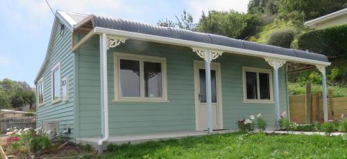 a green tiny house with a pitched roof at Fantail Cottage in Oamaru