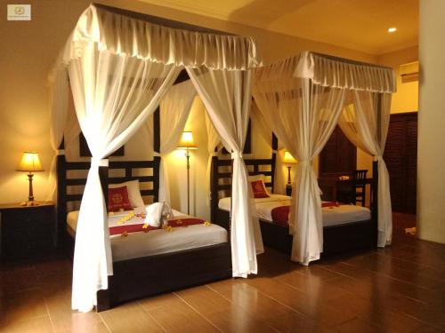 2 camas en una habitación de hotel con cortinas en Bali Nibbana Resort, en Umeanyar